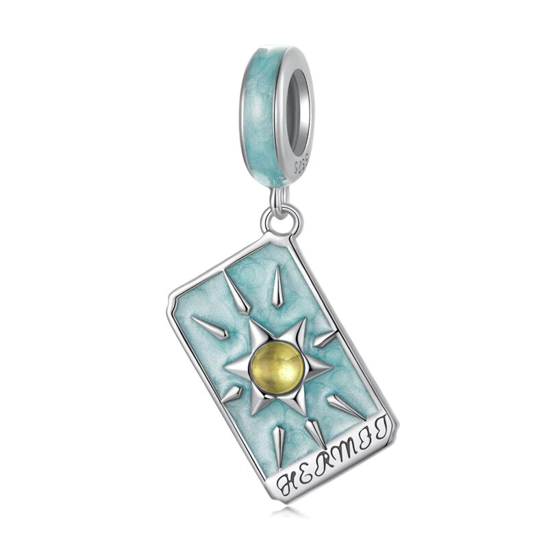 Zawieszka charms w kształcie karty tarota z napisem \'HERMIT\'. Charms jest w kolorze srebrnym z niebieskim tłem i centralnym żółtym elementem.