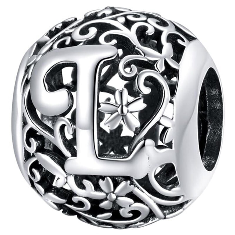 Srebrna zawieszka charms z literą \'L\' otoczona ozdobnym wzorem z kwiatami i wijącymi się liniami. Wzór jest ażurowy, co nadaje zawieszce elegancki wygląd.