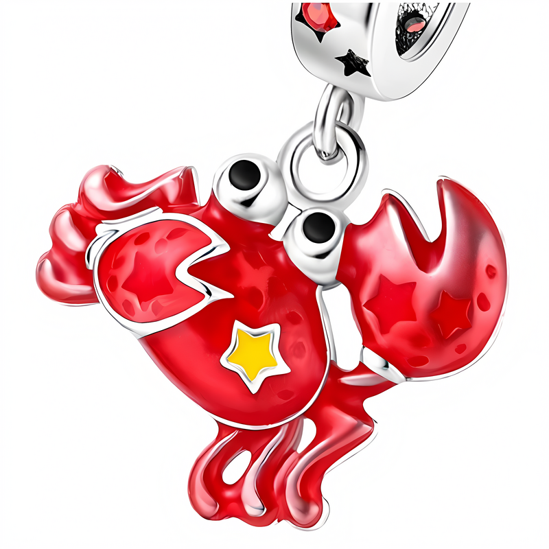 Zawieszka charms w kształcie czerwonego kraba z żółtą gwiazdką na korpusie i czerwonymi gwiazdkami na szczypcach. Elementy metalowe są srebrne z czarnymi i czerwonymi detalami.