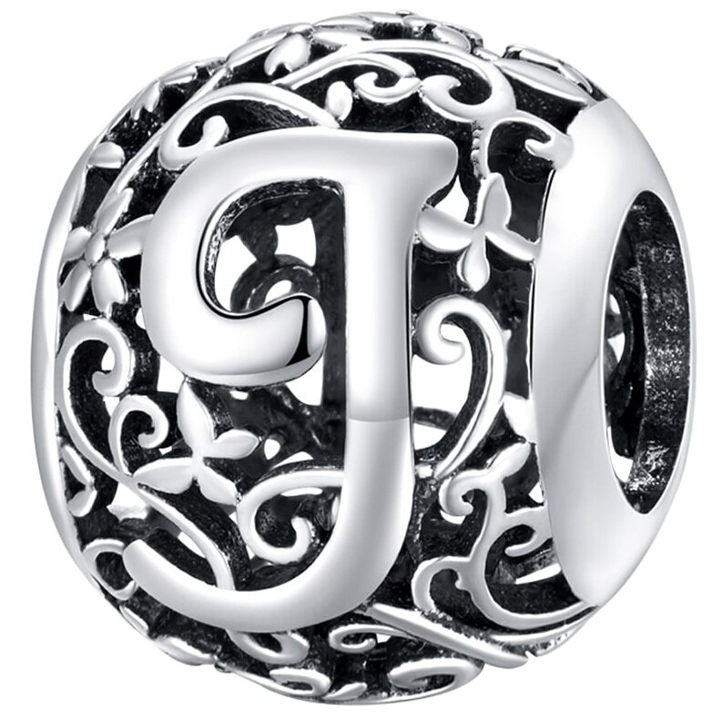 Srebrna zawieszka charms z literą \'J\' otoczona ozdobnym, ażurowym wzorem z motywem roślinnym. Wykonana z połyskującego srebra 925.