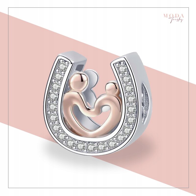 Srebrny charms w kształcie podkowy z ozdobnymi kamieniami, wewnątrz którego znajdują się dwie stylizowane postacie. W prawym górnym rogu widoczny jest napis \'MODA Jewelry\'.