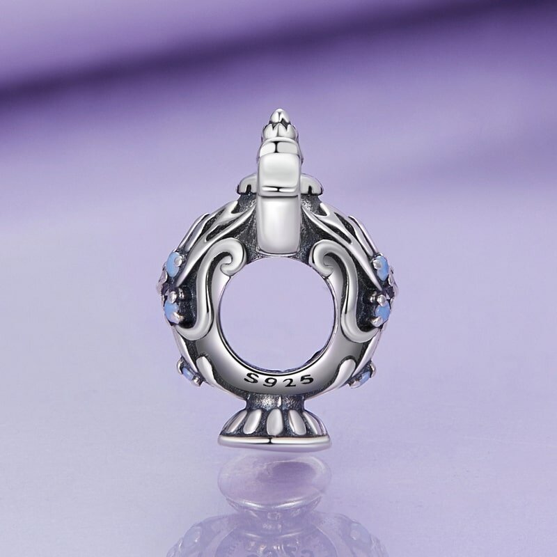 Srebrna zawieszka charms w kształcie lampy z ozdobnymi detalami i niebieskimi kamieniami. Na dolnej części widoczny jest napis \'S925\'.