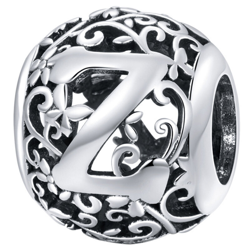 Srebrna zawieszka charms z literą \'Z\' otoczona ozdobnymi, ażurowymi wzorami kwiatowymi.