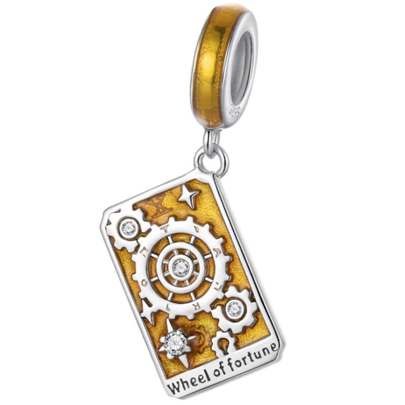 Zawieszka charms w kształcie karty tarota z napisem \'Wheel of fortune\', ozdobiona motywem zębatek i kryształkami na złotym tle.