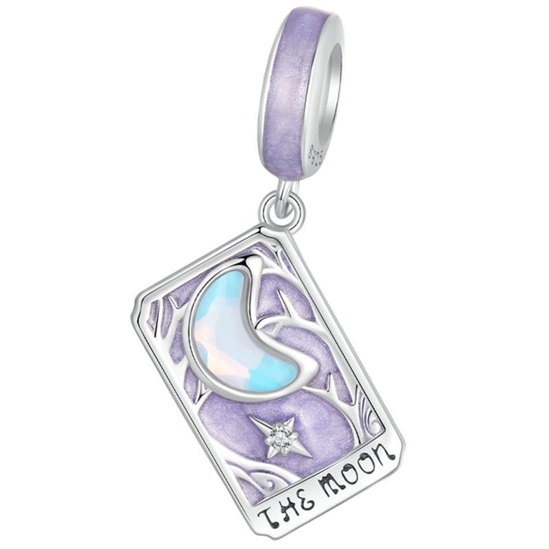 Zawieszka charms w kształcie karty tarota z napisem \'THE MOON\', ozdobiona fioletowym tłem i księżycem z opalizującego materiału.