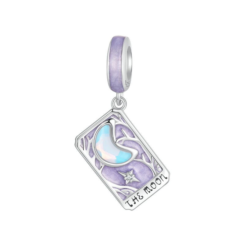 Srebrna zawieszka charms w kształcie karty tarota z napisem \'THE MOON\', ozdobiona motywem księżyca i gwiazdy na fioletowym tle.
