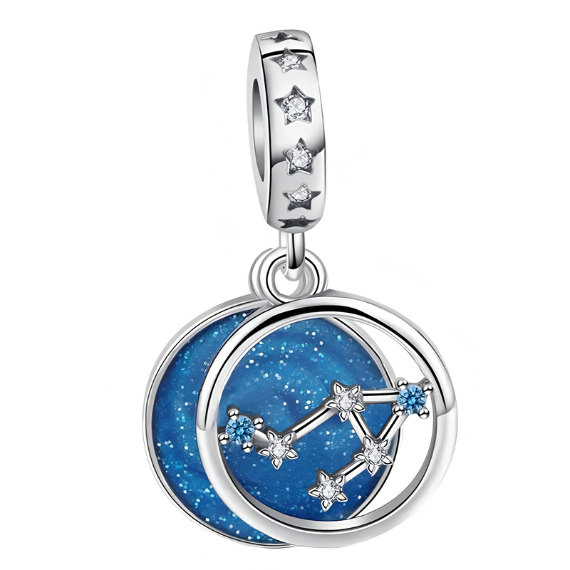 Srebrna zawieszka charms z motywem gwiazdozbioru na niebieskim tle, ozdobiona małymi gwiazdkami. Element mocujący zawiera wycięte gwiazdki z przezroczystymi kamieniami.