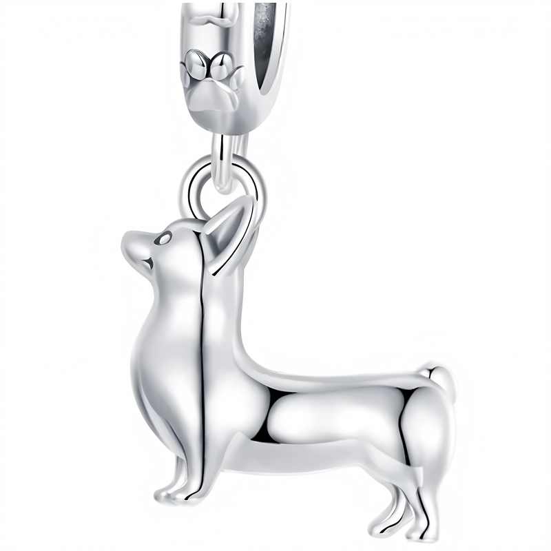 Srebrna zawieszka w kształcie psa rasy Corgi, wykonana z połyskującego metalu. Na uchwycie widoczny jest symbol łapki.