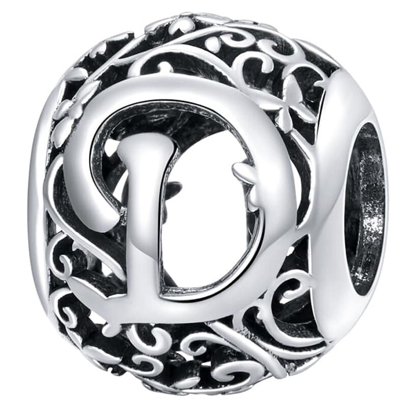 Srebrna zawieszka charms z literą \'D\' otoczona ozdobnym, ażurowym wzorem. Wzór składa się z delikatnych, wijących się linii i motywów roślinnych.