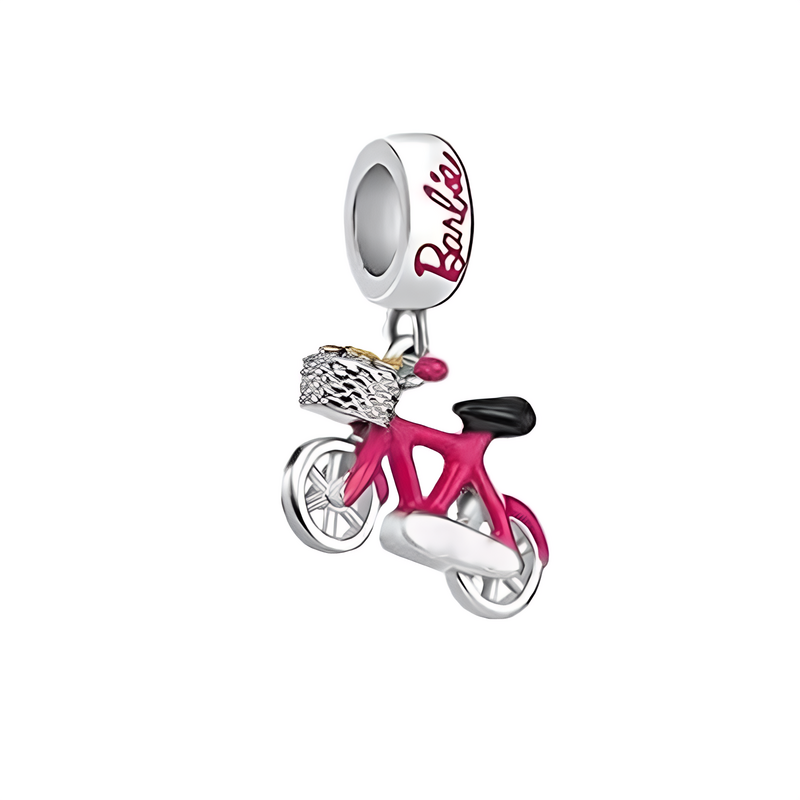 Zawieszka charms w kształcie różowego roweru z koszykiem, przymocowana do srebrnego pierścienia z napisem \'Barbie\'.