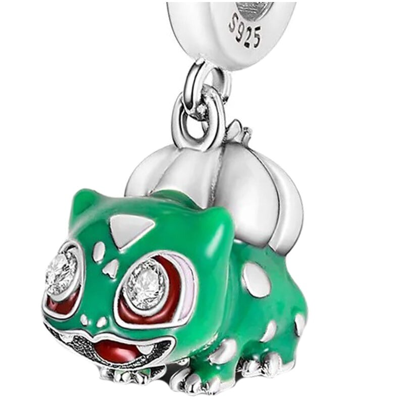 Zawieszka charms w kształcie zielonego stworka z dużymi, błyszczącymi oczami i białymi plamkami na ciele. Na metalowym uchwycie widoczny jest napis \'S925\'.