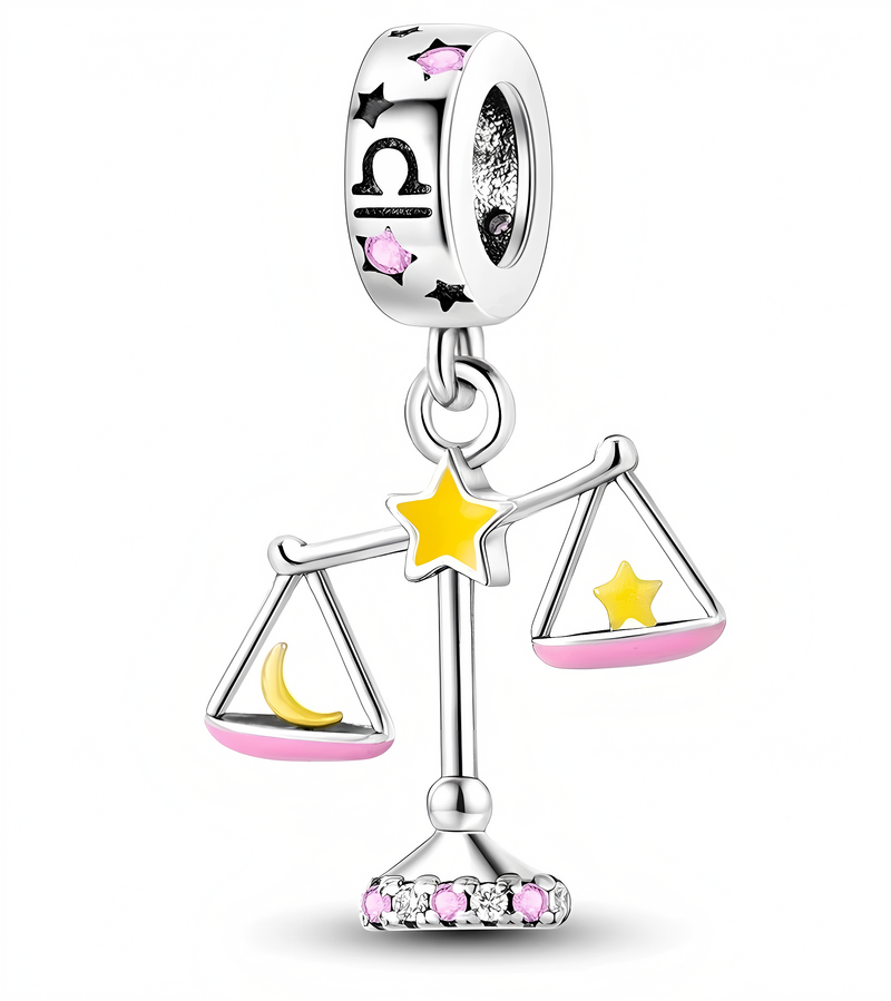 Zawieszka charms w kształcie wagi z żółtą gwiazdą na środku, z różowymi i czarnymi elementami ozdobnymi. Na górnej części widoczny jest symbol znaku zodiaku Waga oraz różowe kamienie.