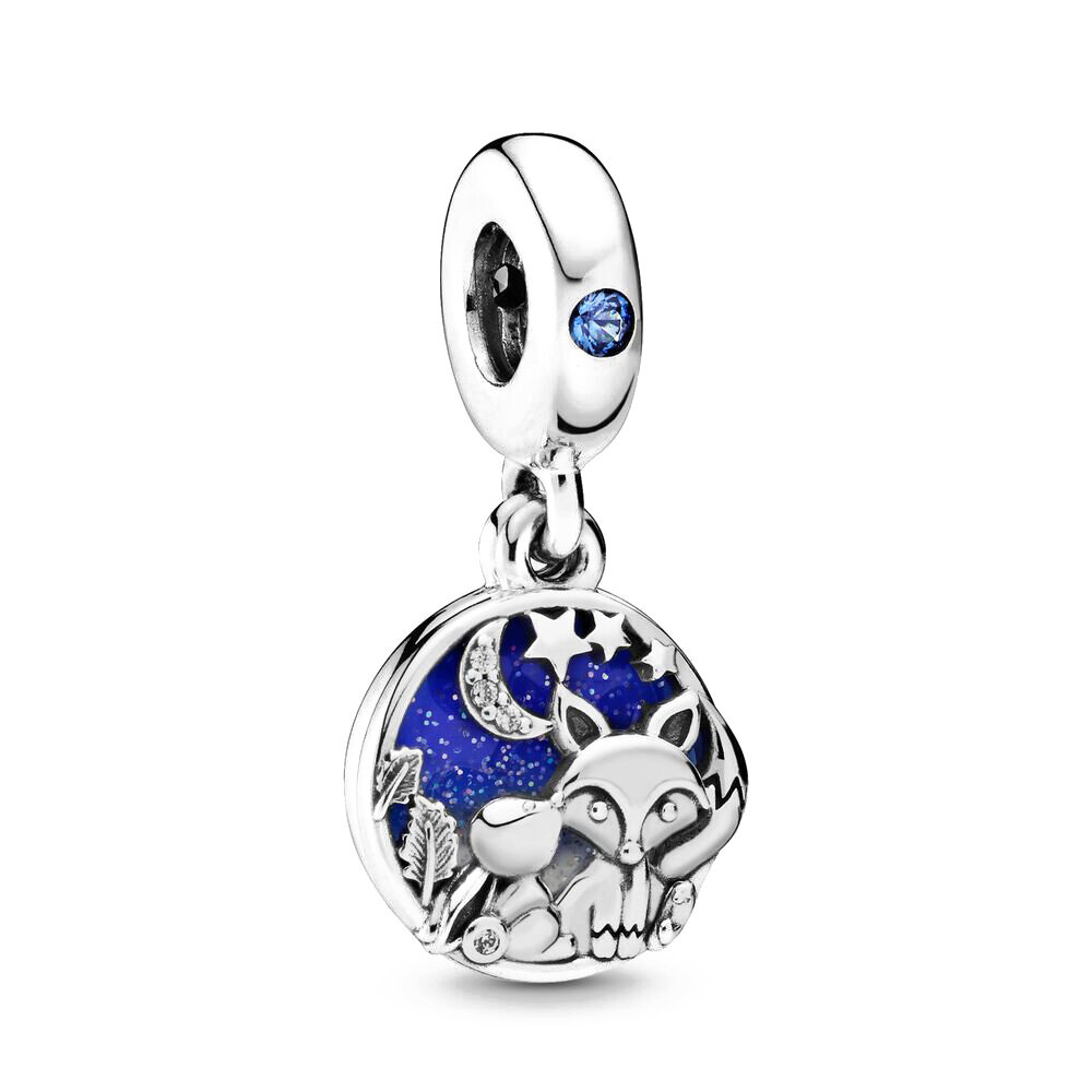 Zawieszka charms przedstawia lisa i królika na tle nocnego nieba z księżycem i gwiazdami. Elementy są wykonane z metalu, a niebo jest w kolorze niebieskim z brokatowym efektem.