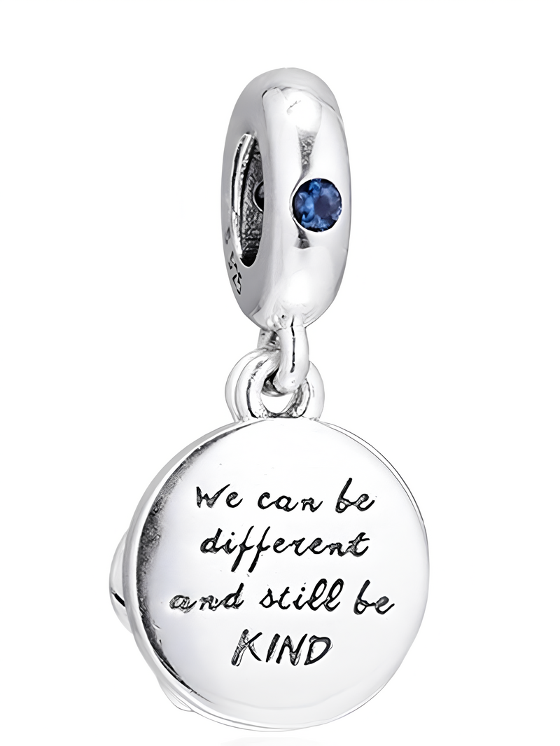 Srebrna zawieszka z niebieskim kamieniem i okrągłym wisiorkiem z napisem: \'We can be different and still be KIND\'.