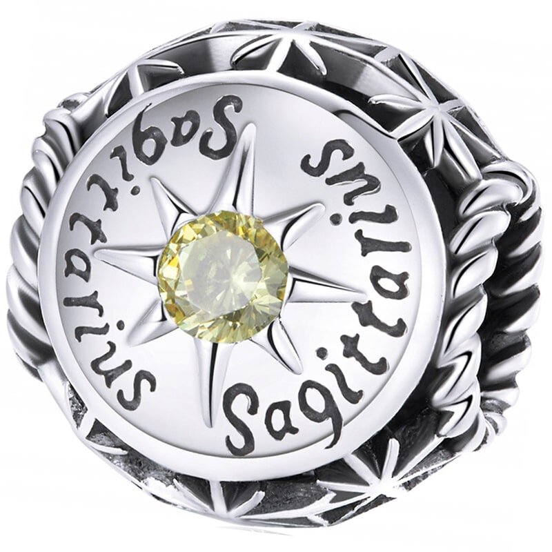 Srebrny charms z napisem \'Sagittarius\' i żółtym kamieniem w centrum, otoczony wzorem przypominającym gwiazdy.