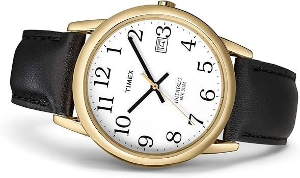 Zegarek z okrągłą, złotą kopertą i białą tarczą z czarnymi cyframi arabskimi. Na tarczy widoczne są napisy: \'TIMEX\', \'INDIGLO\', \'WR 30M\' oraz okienko datownika.