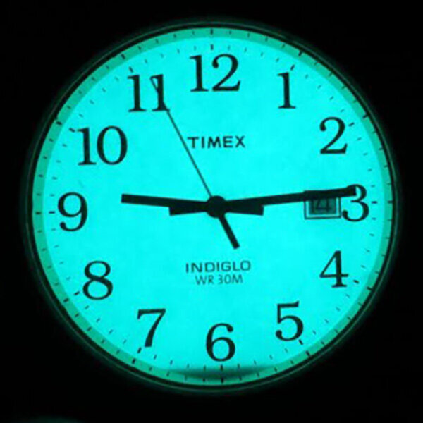 Zegarek z podświetlaną tarczą w kolorze niebieskim, z czarnymi wskazówkami i cyframi arabskimi. Na tarczy widoczne są napisy: \'TIMEX\', \'INDIGLO\', \'WR 30M\' oraz okienko datownika z liczbą \'24\'.