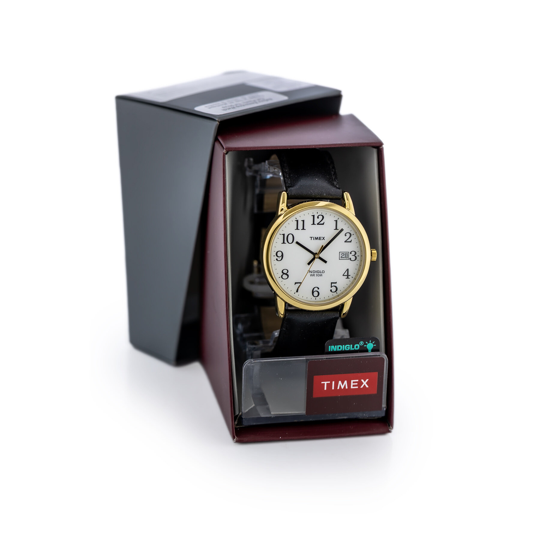 Zegarek męski z białą tarczą i czarnym paskiem, umieszczony w pudełku. Na tarczy widoczne są czarne cyfry oraz logo \'TIMEX\', a na pudełku napis \'TIMEX\'.