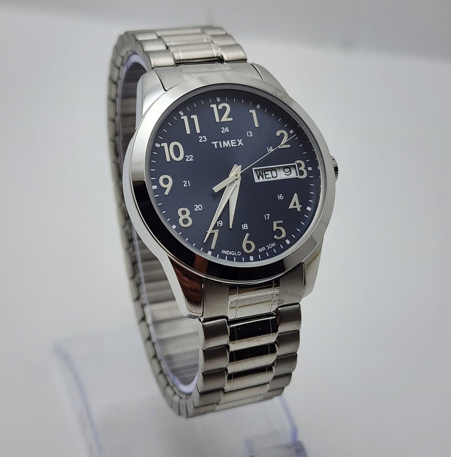 Zegarek męski z metalową bransoletą i czarną tarczą, na której widoczne są białe cyfry oraz wskazówki. Na tarczy znajduje się logo \'TIMEX\' oraz okienko z datą \'WED 9\'.