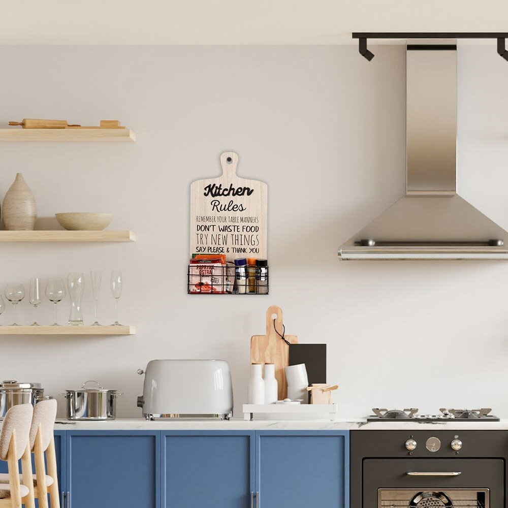 Kuchnia z niebieskimi szafkami, na blacie stoi toster i naczynia. Na ścianie wisi tablica z napisem: \'Kitchen Rules Remember your table manners Don\'t waste food Try new things Say please & thank you\'.