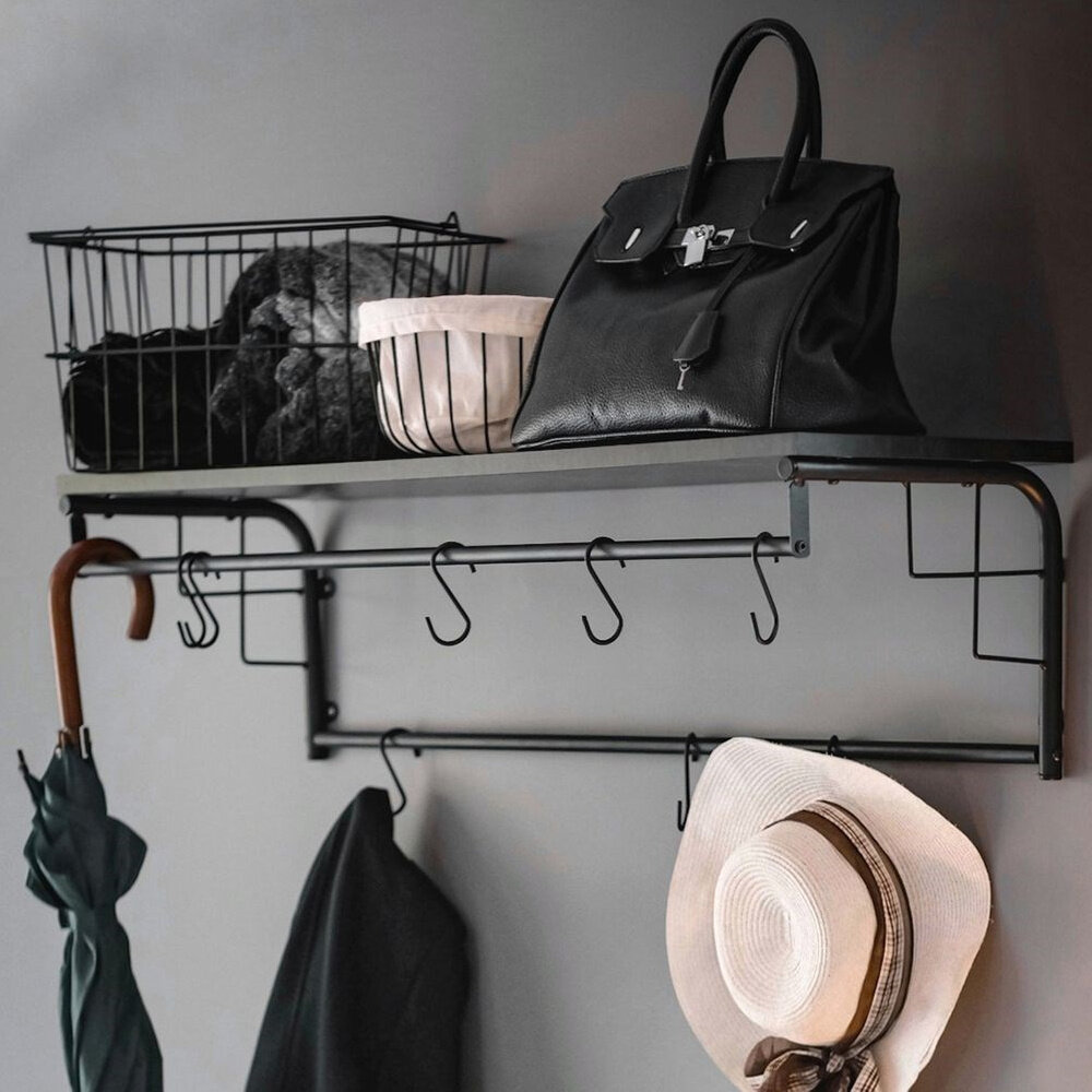 Czarny wieszak ścienny z półką, na której znajdują się torba i kosze. Na wieszaku wiszą parasol, płaszcz i kapelusz.