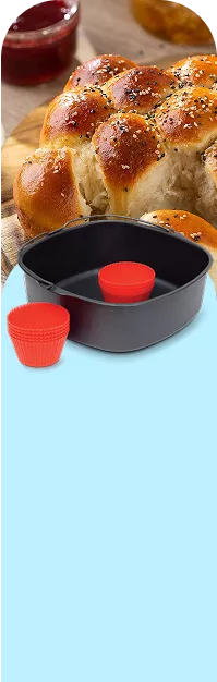 Na drewnianej desce leży pieczywo z posypką, obok znajduje się czarna miska z czerwonymi silikonowymi foremkami. Tło jest jasnoniebieskie.