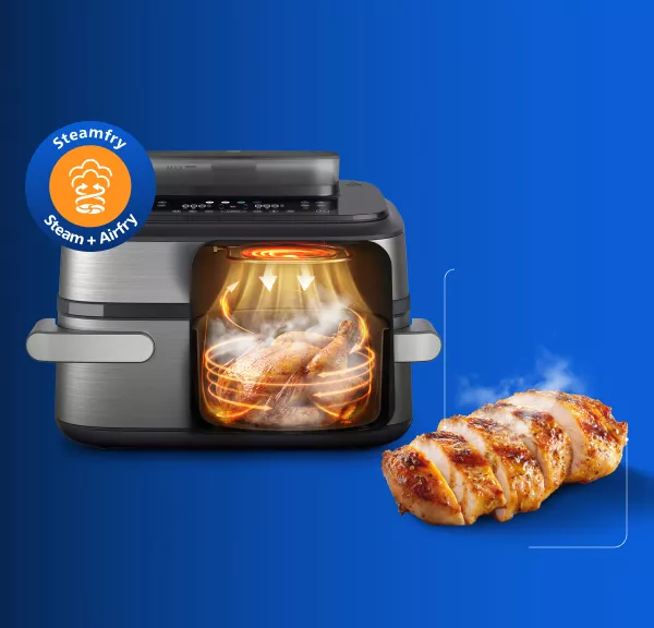 Na niebieskim tle widoczna jest frytkownica beztłuszczowa z przezroczystym frontem, przez który widać pieczone mięso. Obok znajduje się kawałek upieczonego mięsa, a w lewym górnym rogu widnieje okrągłe logo z napisem \'Steamfry Steam + Airfry\'.