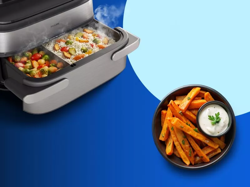 Obraz przedstawia otwartą frytkownicę beztłuszczową z widocznymi warzywami w środku oraz miskę z frytkami i sosem. Na frytkownicy widoczne jest logo \'Philips\'.