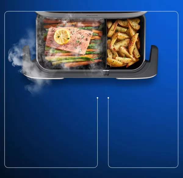 Obraz przedstawia wnętrze frytkownicy beztłuszczowej z dwoma komorami. W jednej komorze znajduje się łosoś z plasterkiem cytryny i warzywami, a w drugiej pieczone ziemniaki.