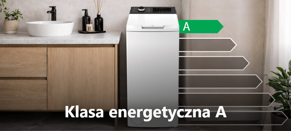 Pralka w białym kolorze stoi w łazience obok drewnianej szafki z umywalką. Na obrazie widoczny jest napis \'Klasa energetyczna A\'.