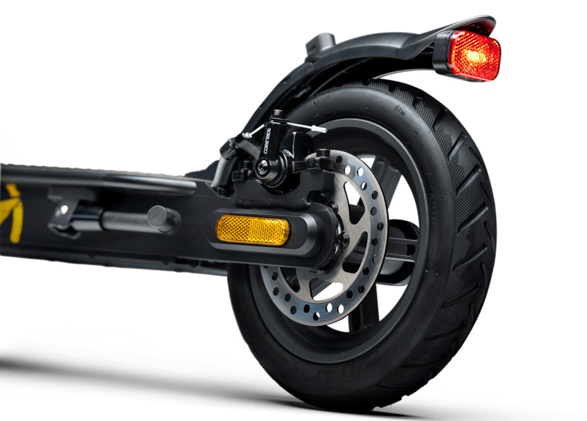 Zdjęcie przedstawia tylne koło hulajnogi elektrycznej z widocznym hamulcem tarczowym i czerwonym światłem. Na ramie znajduje się żółty odblask.