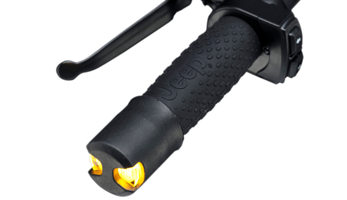 Czarna, gumowa rączka hulajnogi z wypukłym napisem \'Jeep\' oraz żółtymi elementami na końcu. Widoczna jest także część hamulca ręcznego.