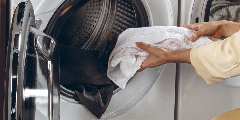 PRALKA HAIER HW90G-BD14979U1S lifestyle wizualizacja bęben otwarta pralka środek wnętrze dłoń dokładanie ręcznik drzwiczki Skuteczne pranie w zimnej wodzie Quick & Clean niska temperatura usuwanie trudnych plam