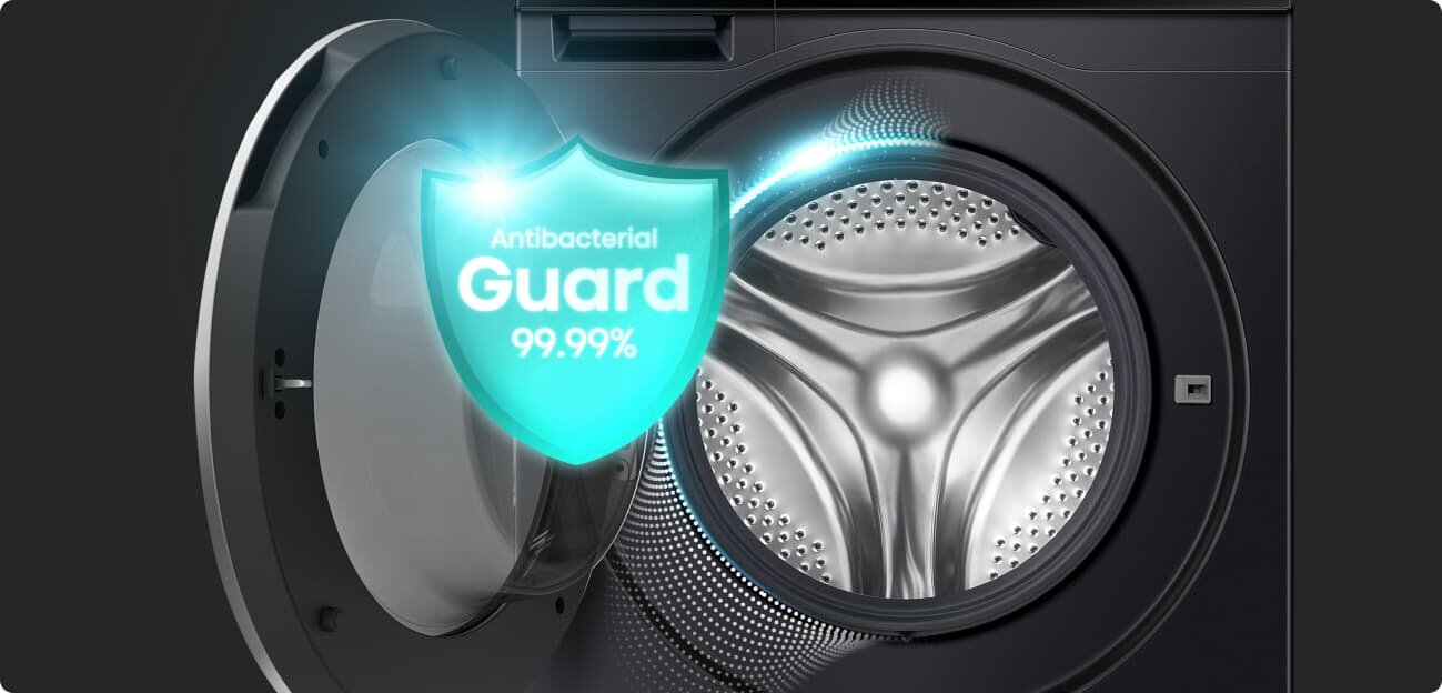 Obraz przedstawia otwartą pralkę z widocznym bębnem. Na drzwiach pralki znajduje się grafika z napisem \'Antibacterial Guard 99.99%\'.
