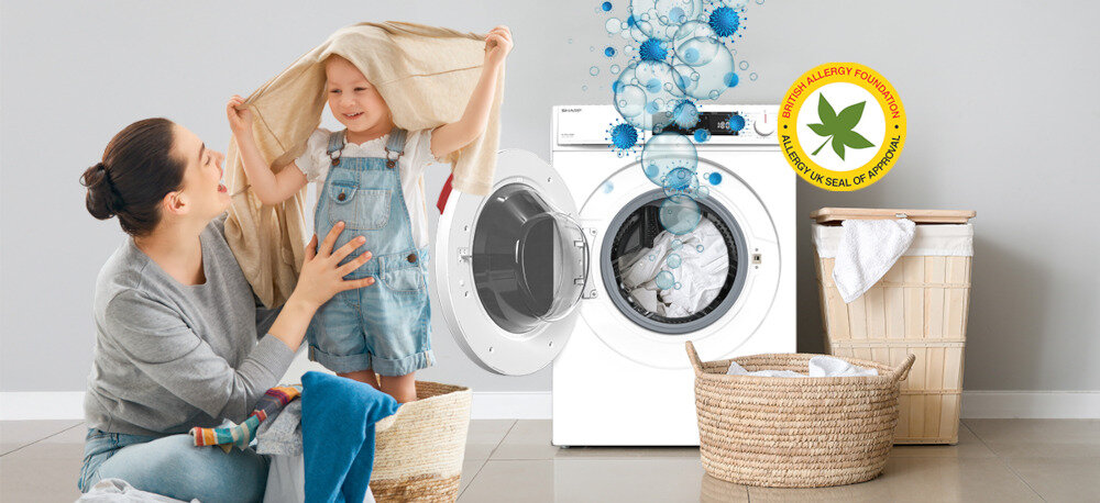 PRALKA SHARP ES-NFA612DWB-PL Na podłodze siedzi kobieta oraz dziecko, które zakłada na głowę jasny ręcznik lub tkaninę. W tle znajduje się biała pralka z otwartymi drzwiczkami i graficznymi bąbelkami, obok widoczne są dwa kosze na pranie oraz pojemnik na brudną odzież. W prawym górnym rogu widnieje okrągły znak potwierdzający rekomendację dla alergików (British Allergy Foundation) Allergy Smart usuwanie alergenów bakterii roztoczy higiena prania wyższa temperatura dokładne płukanie tekstylia domowe alergicy niemowlęta dzieci wrażliwa skóra miękkie ubrania świeżość bezpieczeństwo czystość