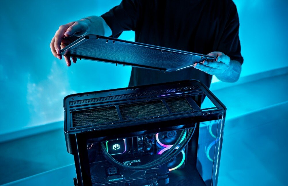 Osoba trzyma panel obudowy komputera, ukazując wnętrze z podświetleniem RGB i widoczną kartą graficzną z napisem \'GeForce GTX\'.
