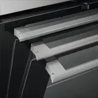 Obraz przedstawia fragment piekarnika z widocznymi trzema metalowymi uchwytami na drzwiach. Piekarnik ma czarną obudowę.