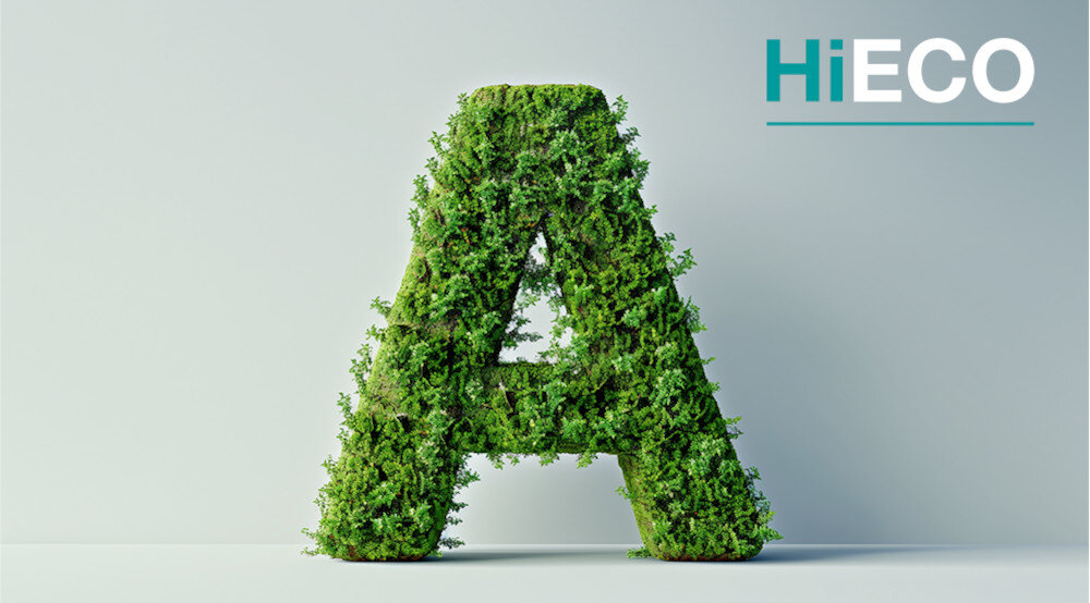 Duża litera \'A\' pokryta zielonymi liśćmi na jasnym tle. W prawym górnym rogu widoczny jest napis \'HiECO\'.