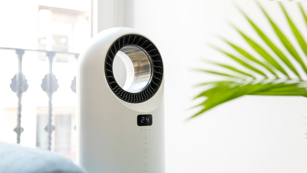 Na obrazie widoczny jest biały termowentylator o nowoczesnym designie z okrągłym otworem pośrodku. Na urządzeniu wyświetlana jest liczba \'24\'.