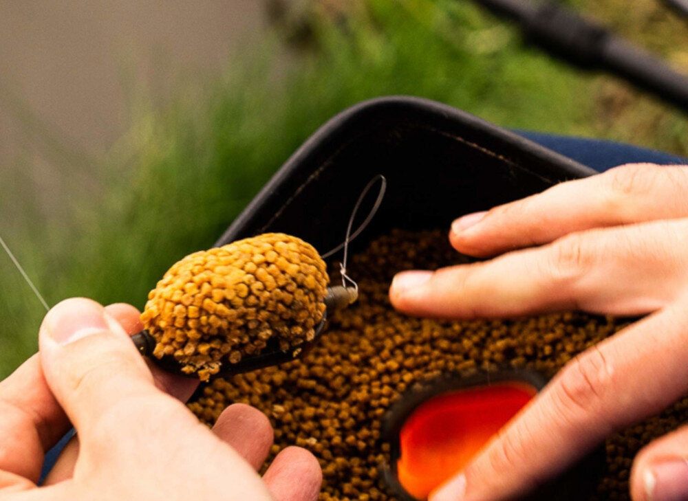 Pellet BAITNOW Original Coarse 2 mm (800 g) widoczne przygotowanie koszyczka z zanętą w środowisku naturalnym pellet 2 mm drobna frakcja stopniowe uwalnianie naturalna barwa intensywny rybny zapach zawartość tłuszczu i białka naturalna barwa karp lin leszcz karaś