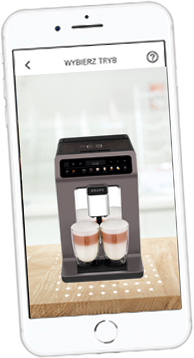 Na ekranie smartfona widoczny jest ekspres do kawy z dwoma filiżankami z mleczną pianką. Na górze ekranu znajduje się tekst \'WYBIERZ TRYB\'.