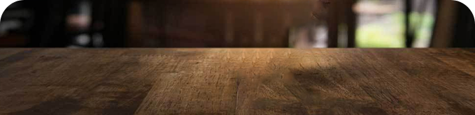 Drewniany stół z widocznymi słojami i delikatnym oświetleniem w tle.