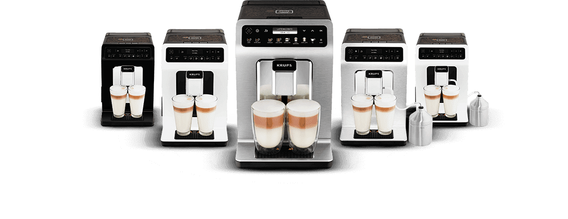 Na obrazie widocznych jest pięć ekspresów do kawy z logo KRUPS, każdy z dwoma szklankami wypełnionymi kawą z mleczną pianką. Ekspresy mają srebrne i czarne elementy oraz wyświetlacze z przyciskami.