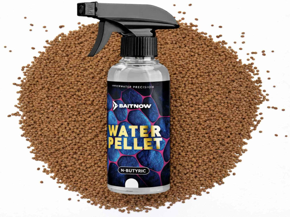 Butelka z rozpylaczem o nazwie \'BAITNOW WATER PELLET N-BUTYRIC\' stoi na tle brązowych granulek. Na etykiecie widnieje napis \'UNDERWATER PRECISION\'.