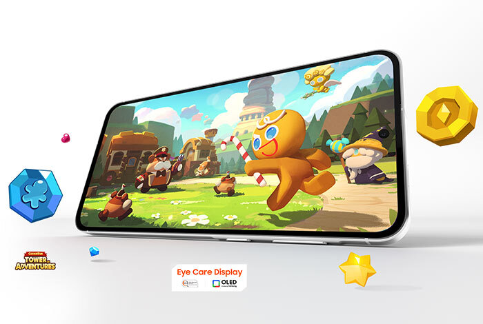 Smartfon wyświetla kolorową grafikę z postaciami z gry, w tym ciastko z laską cukrową. Na dole widoczny jest tekst: \'Eye Care Display\' oraz logo \'OLED\'.