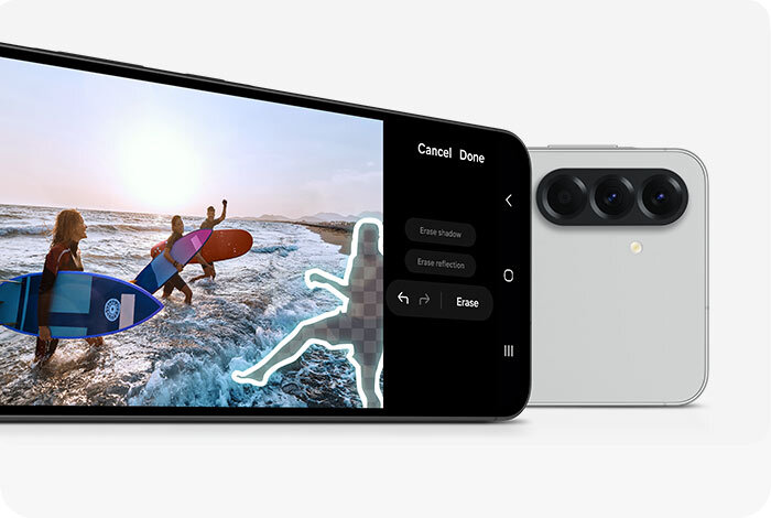 Na obrazie widoczny jest smartfon z wyświetlaczem pokazującym edytowane zdjęcie osób z deskami surfingowymi na plaży. Obok znajduje się tył smartfona z trzema obiektywami aparatu i lampą błyskową.