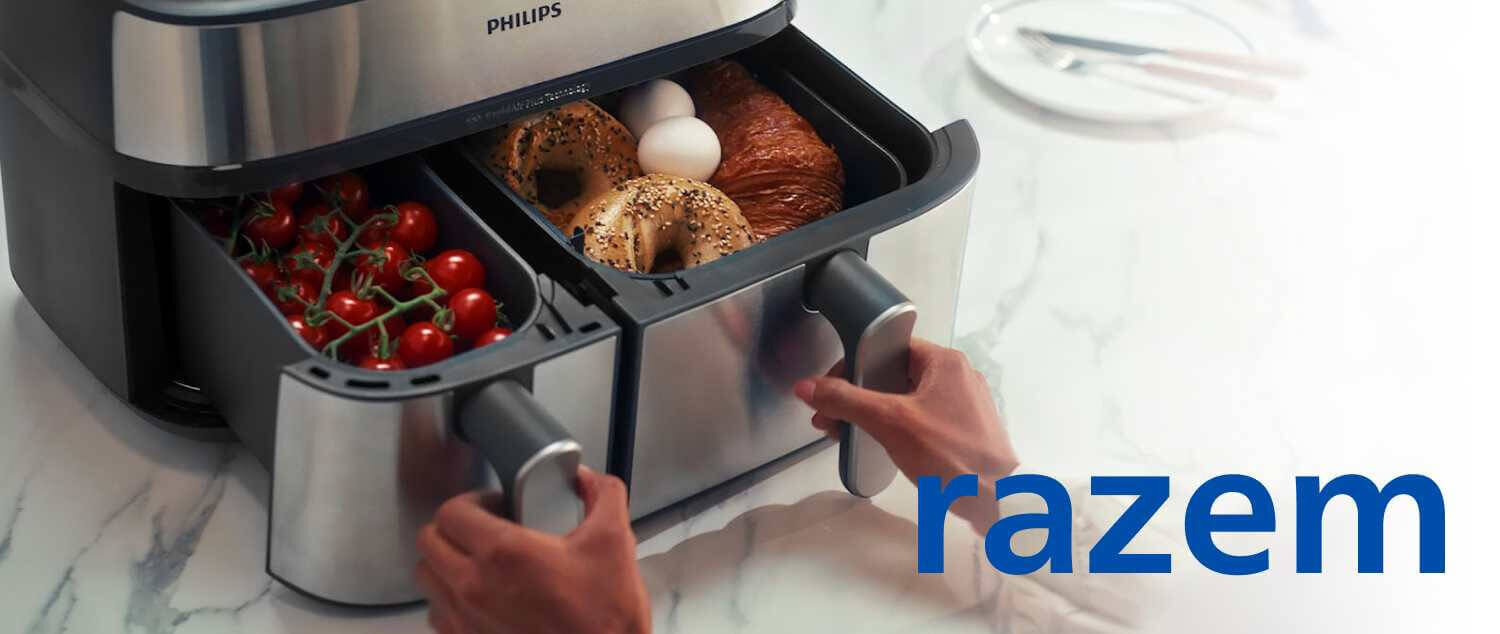 Osoba otwiera dwa kosze frytkownicy beztłuszczowej marki PHILIPS, w których znajdują się pomidorki koktajlowe, bajgle, jajka i rogalik. Na obrazie widoczny jest napis \'razem\'.