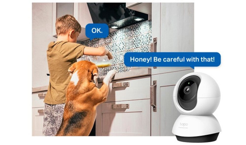 Chłopiec i pies stoją przy kuchennym blacie, a obok widoczna jest kamera TP-LINK Tapo. Na obrazie znajdują się dymki z tekstem: \'OK.\' oraz \'Honey! Be careful with that!\'.