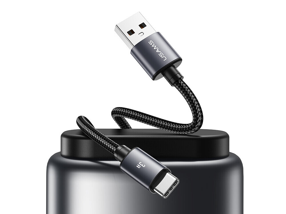 Na obrazie widoczny jest metaliczny kabel USB-C - USB-A z plecionym oplotem, z logo \'USAMS\' na wtyczce USB-A. Kabel jest umieszczony na ciemnym tle, a wtyczka USB-C ma oznaczenie \'3A\'.