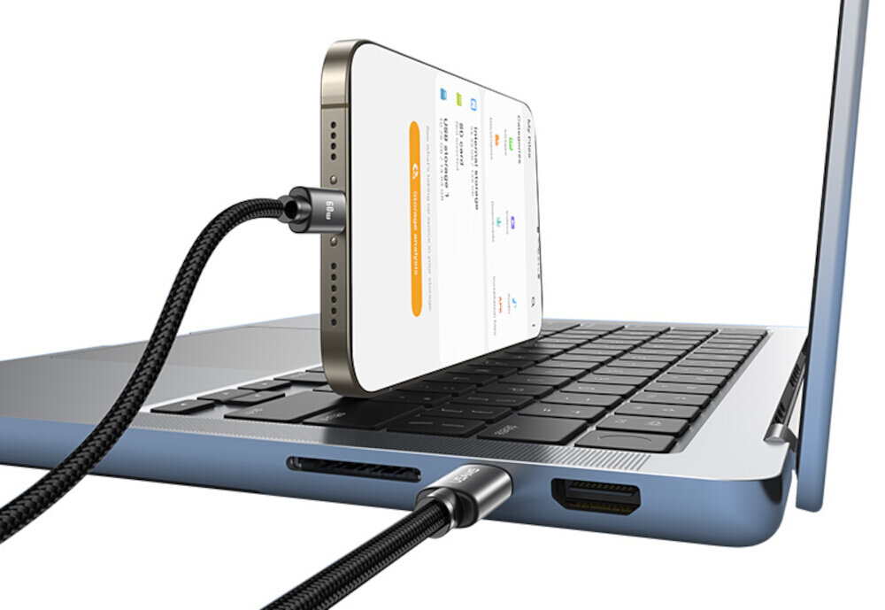 Telefon podłączony do laptopa za pomocą metalicznego kabla USB-C. Na ekranie telefonu widoczny jest interfejs aplikacji z tekstem i ikonami.